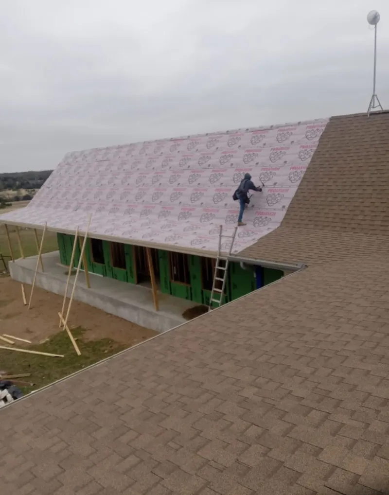 Worker preparing underlayment for a metal roof installation in Marion